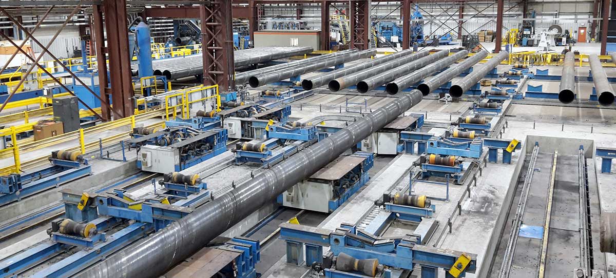 Part of the pipe storage area with transport equipment for the final welding stands.